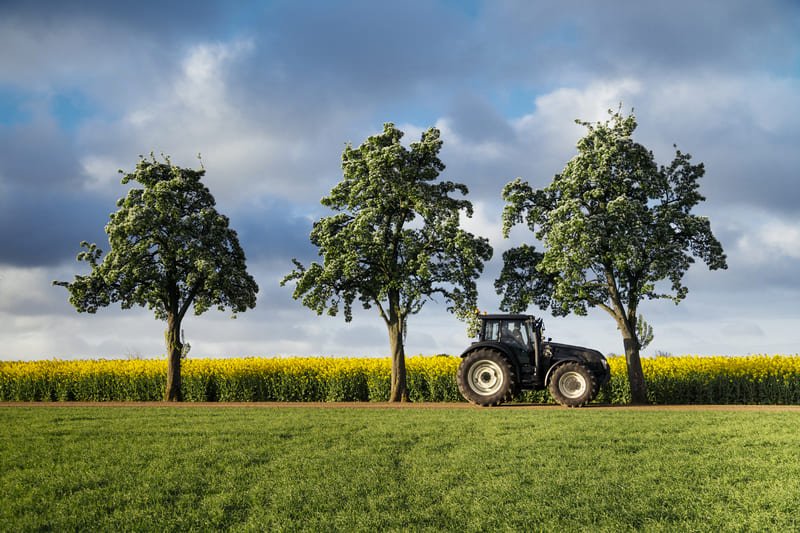 A 4WD farm tractor operates efficiently across a vast green field, showcasing agricultural productivity.