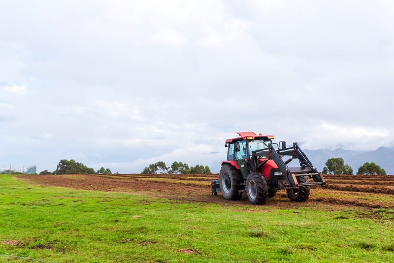 A 4WD farm tractor plowing a field, showcasing its robust design and agricultural utility in action.