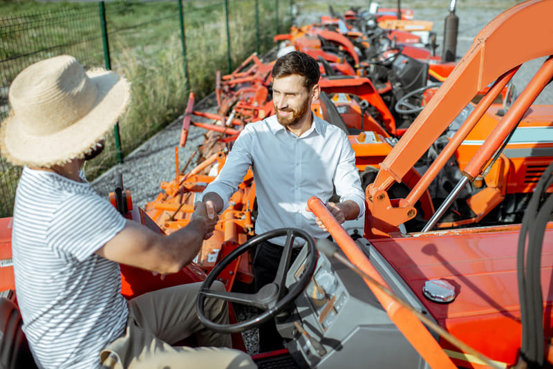 A selection of farm tractors available for purchase, showcasing various models and colors in a rural setting.