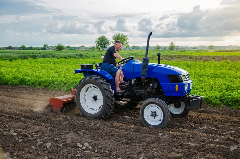 A compact farm tractor designed for efficient agricultural tasks, featuring a sturdy build and versatile attachments.