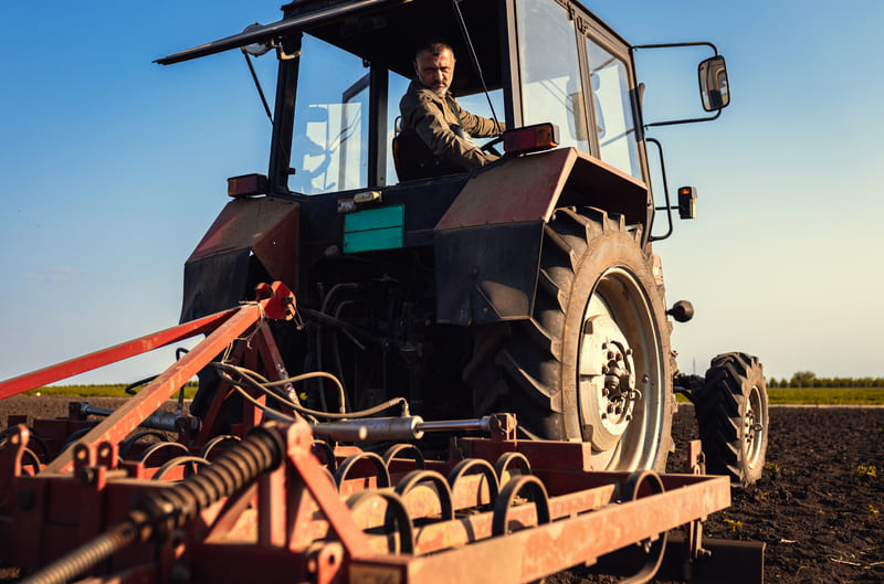 A farmer performing monthly maintenance on a farm tractor, ensuring optimal performance and longevity of the equipment.