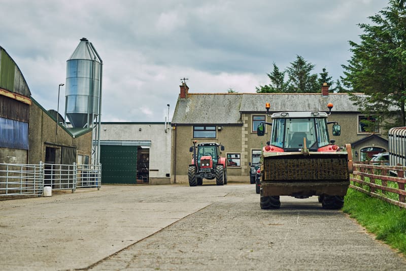 A spacious barn filled with various farm tractors, showcasing their storage and maintenance area.