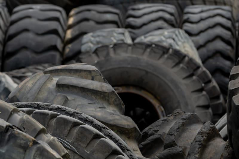 A close-up of old, worn tractor tires showing deep treads and weathered surfaces, symbolizing years of agricultural use.
