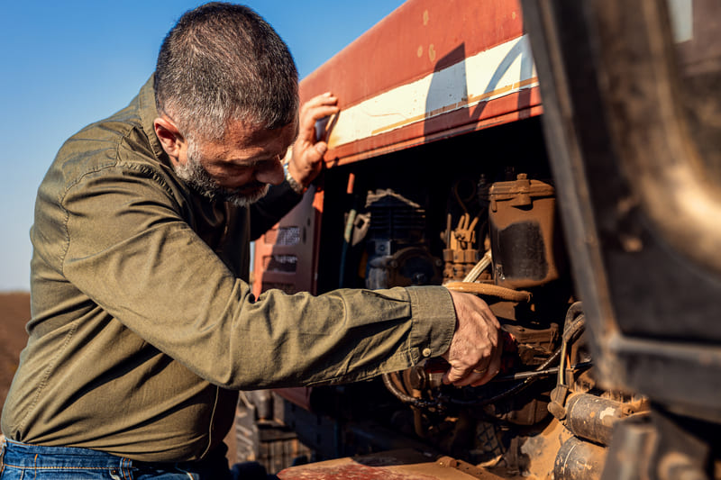 A technician performing maintenance on a tractor, ensuring optimal performance and longevity through careful inspection and care.
