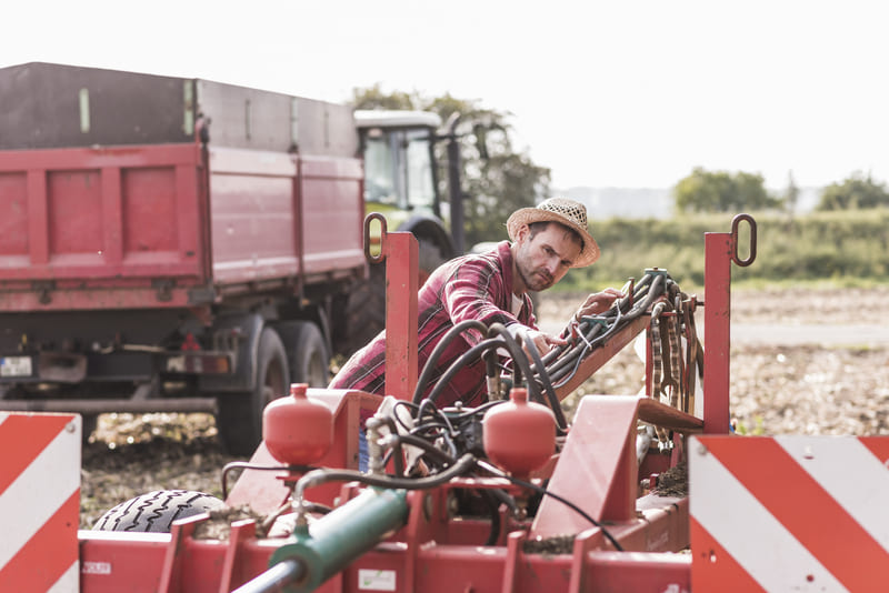 A technician inspects a tractor's PTO system, ensuring proper function and safety for agricultural operations.