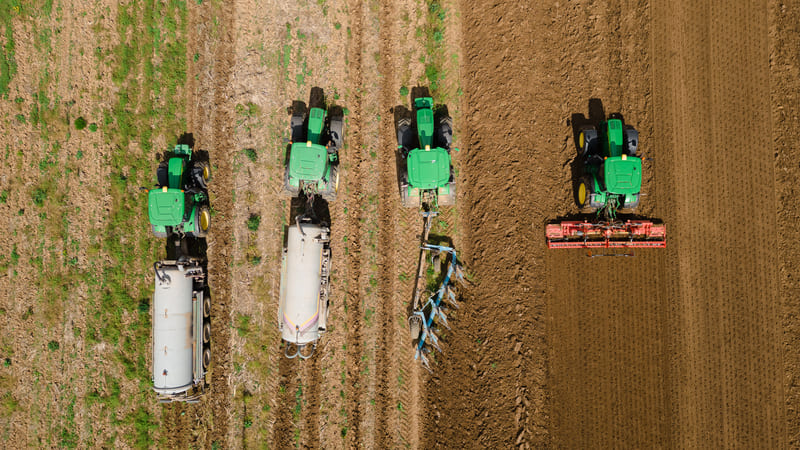 A 4WD farm tractor navigating muddy terrain, showcasing its superior traction and stability.