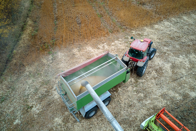 A farm tractor pulling a heavy grain trailer through a field, showcasing its power and hauling capability.