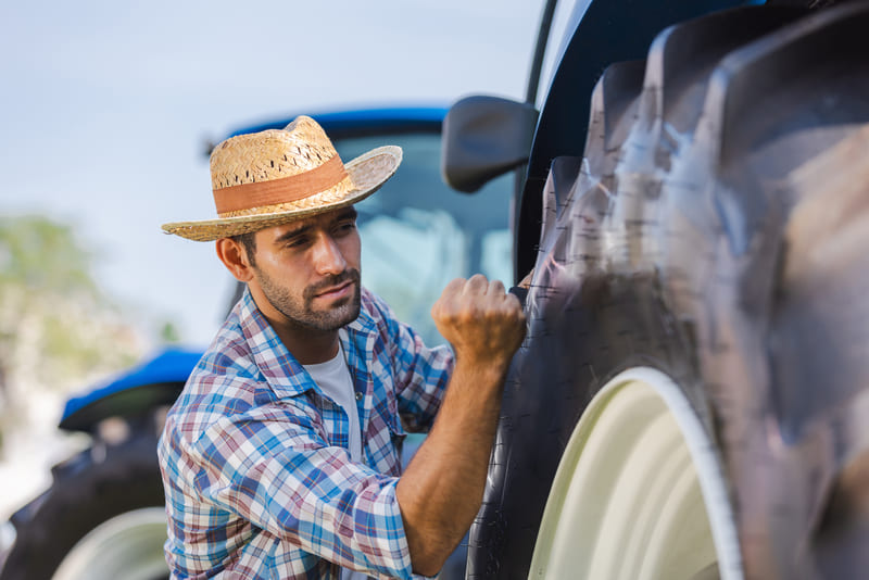 A farmer performing routine maintenance on a farm tractor to ensure efficiency and longevity.
