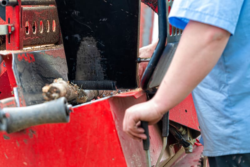A mechanic performing major repairs on a farm tractor, inspecting the engine and hydraulic components.