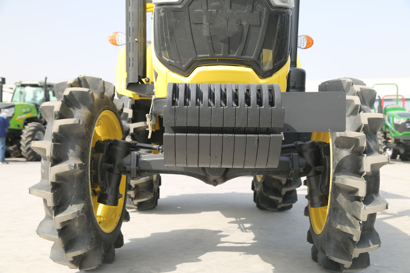 A compact farm tractor navigating through tight spaces in a field, showcasing its maneuverability and control.