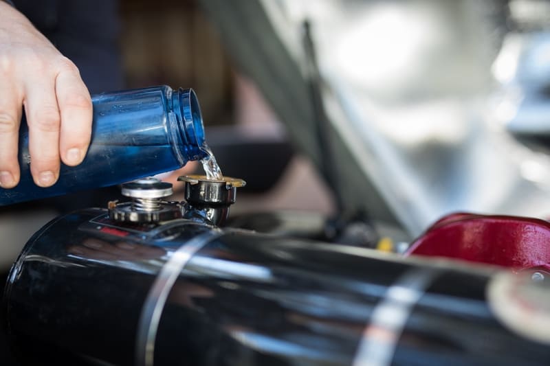 A farmer adding fuel stabilizer to a tractor’s fuel tank to prevent degradation and ensure engine efficiency.