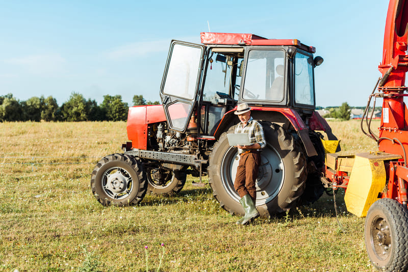 A medium-size farm tractor parked in a field, designed for versatile agricultural tasks with balanced power and efficiency.