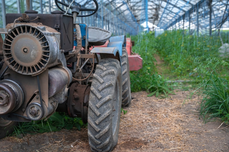 An old farm tractor with a weathered body, parked in a field, showcasing its vintage design and durability.
