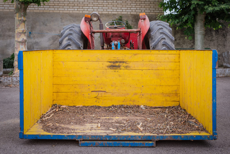 A farmer restarting a stored tractor, checking battery, fluids, and engine components for safe operation.