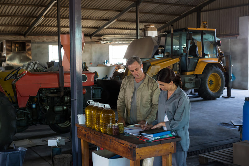 A farmer checking and maintaining tractor fluids, including engine oil, coolant, and hydraulic fluid.