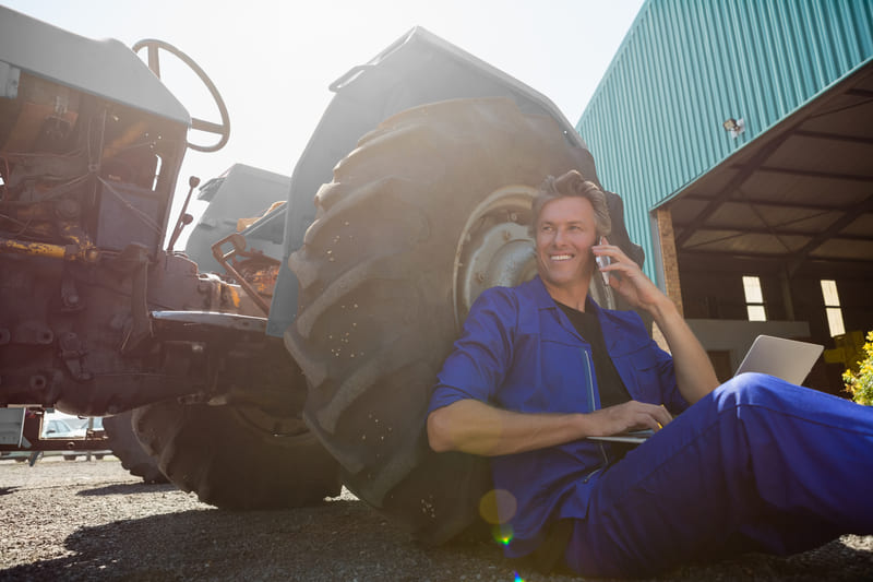 A farmer performing monthly maintenance on a tractor, checking fluids, filters, and tires for optimal performance.