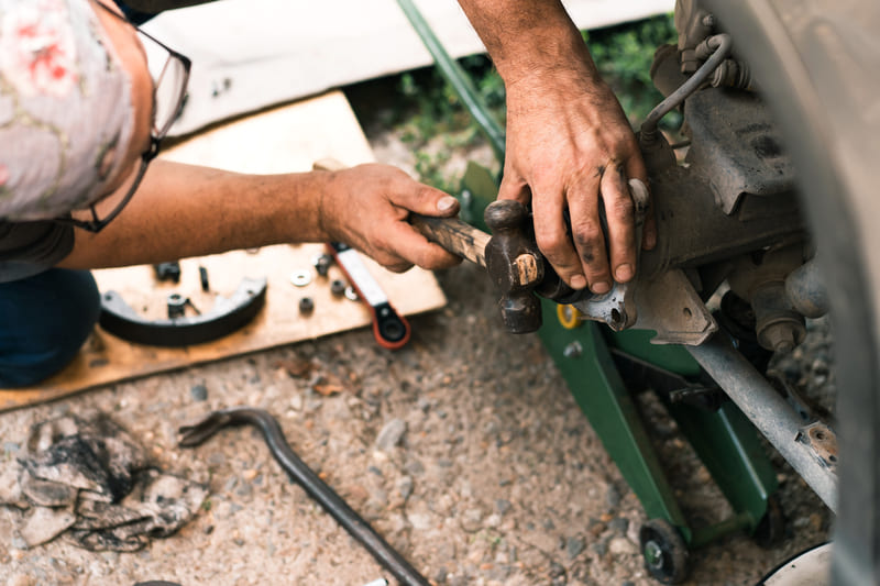A mechanic repairing a utility tractor, inspecting its engine and hydraulic system for performance issues.