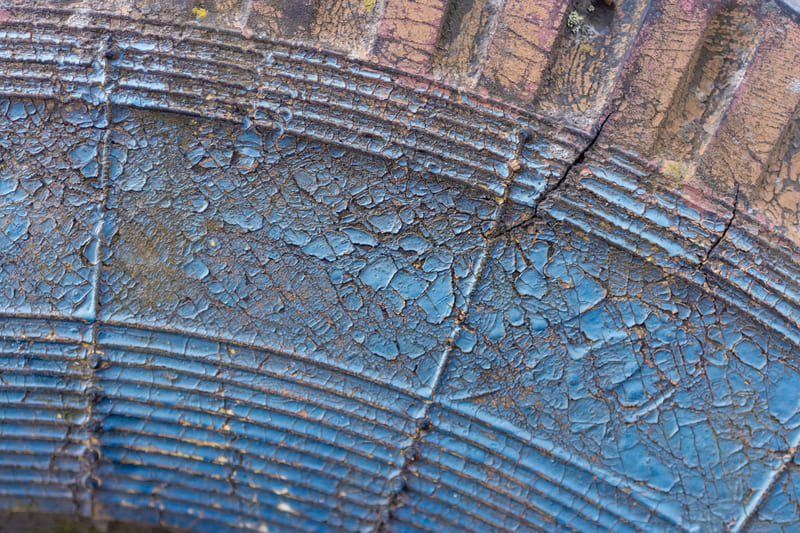 A close-up of a worn farm tractor tire with visible tread wear, cracks, and reduced traction.