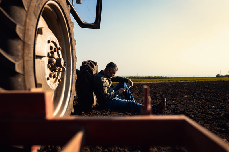 A farm tractor being driven in the field with signs of operator fatigue, highlighting the need for safe driving practices.