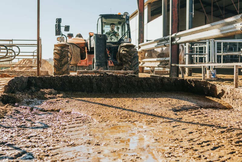 A farm tractor navigating through deep mud, showcasing its powerful traction and rugged durability.