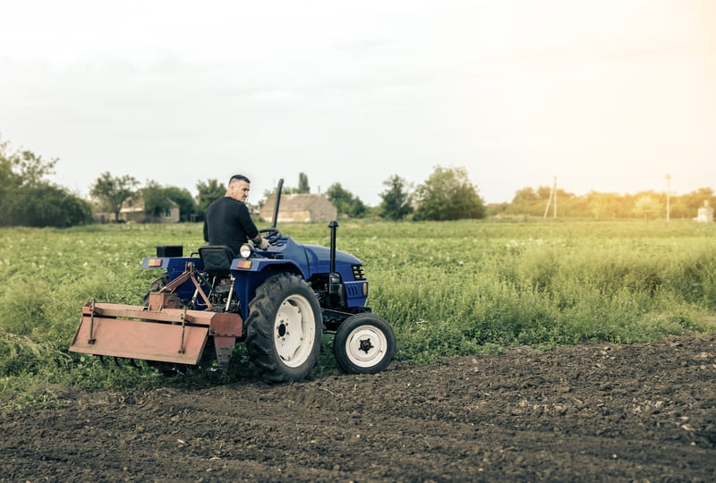 Side-by-side comparison of a utility tractor and a compact farm tractor, illustrating their differences in size, power, and implement compatibility.