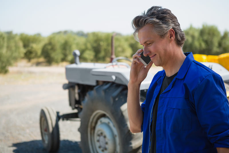 A mechanic repairing a farm tractor in a barn, working on engine components with tools and diagnostic equipment nearby.