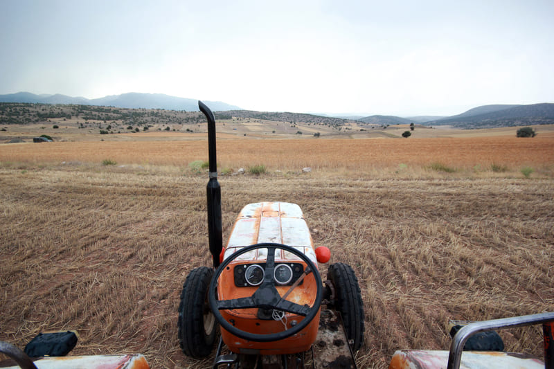 A farm tractor navigating uneven terrain, with its tires gripping over slopes and ruts for stable field operation.