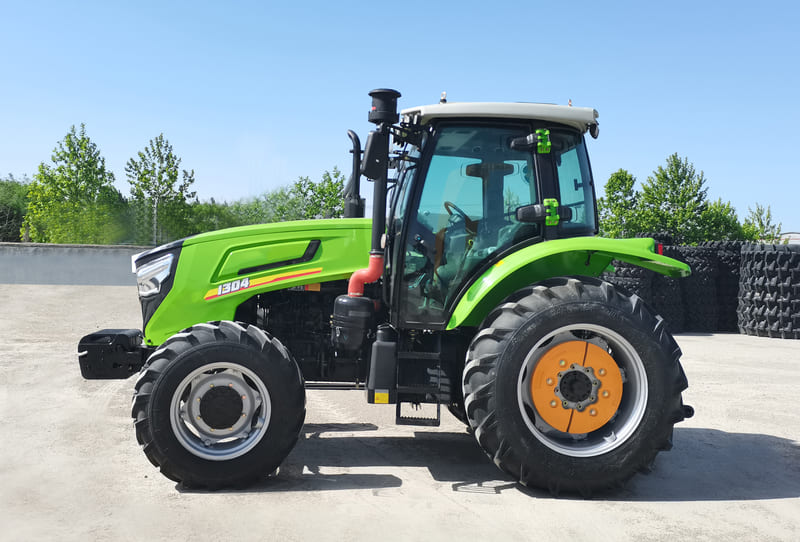 A brand-new farm tractor parked on a cultivated field, gleaming with fresh paint and featuring a modern cab, large rear tires, and advanced controls.