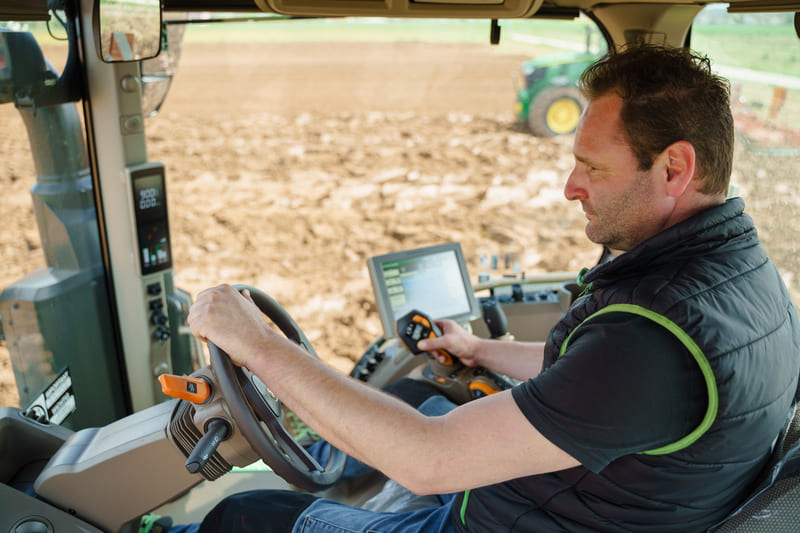 Modern farm tractor equipped with advanced GPS navigation system in a cultivated field.