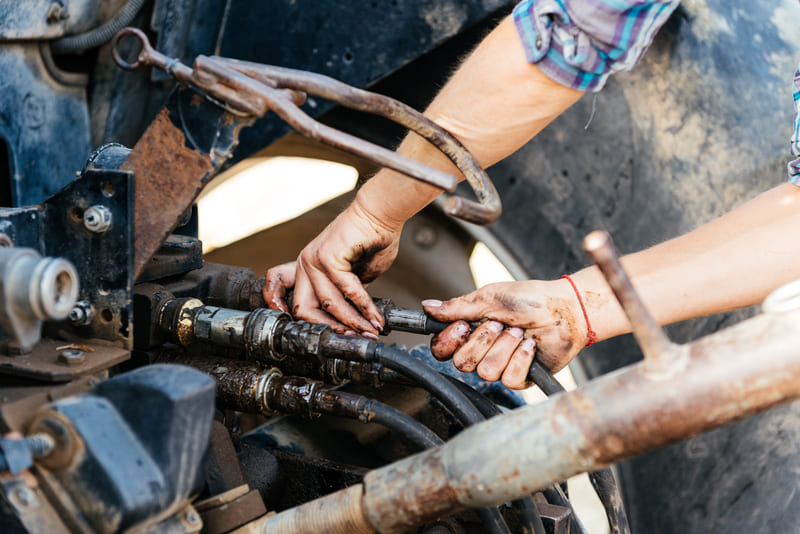 Farmer performing routine tractor maintenance to ensure optimal agricultural machinery performance.