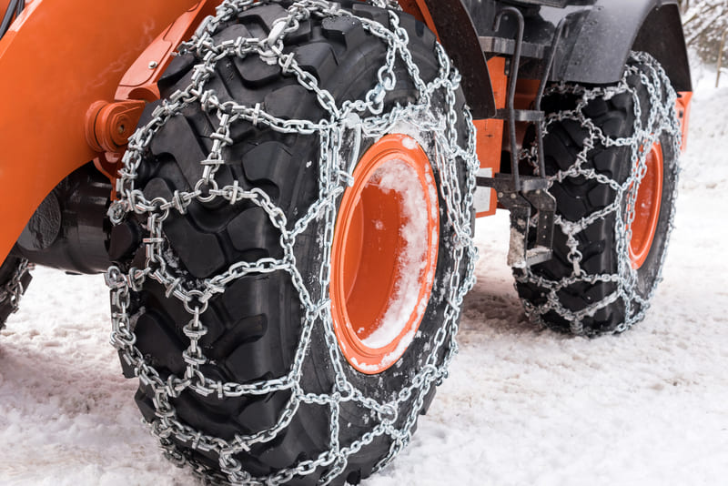 Tractor tires equipped with snow chains for enhanced winter traction on icy farmland.