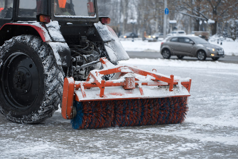 Heavy-duty winter tractor with snow removal attachments clearing snow on a rural road, winter equipment featured.