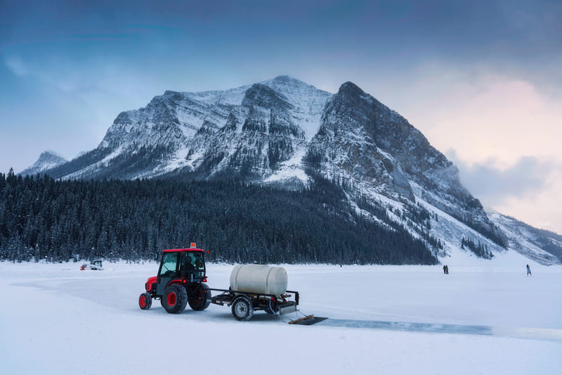 Two winter tractors parked in a snowy field under a cloudy sky, showcasing winter farm machinery.