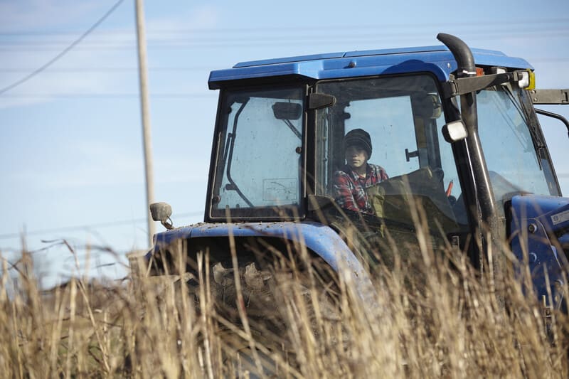Man driving a snow-covered tractor during winter, clearing snowy road, winter tractor operation scene.